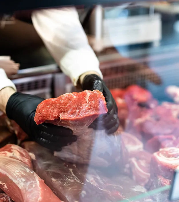 Boucher en gants noirs tient un morceau de viande fraîche dans une vitrine à Bourges dans le Cher 18
