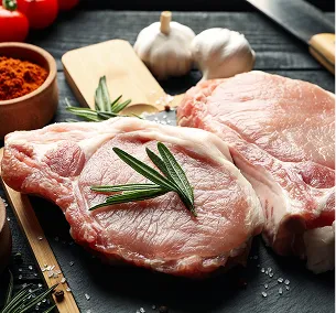 Deux côtelettes de porc crues avec du romarin et des gousses d'ail sur une surface sombre à Bourges dans le Cher 18