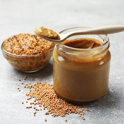 Bocal de moutarde lisse, cuillère, et graines de moutarde sur une table grise à Bourges dans le Cher 18